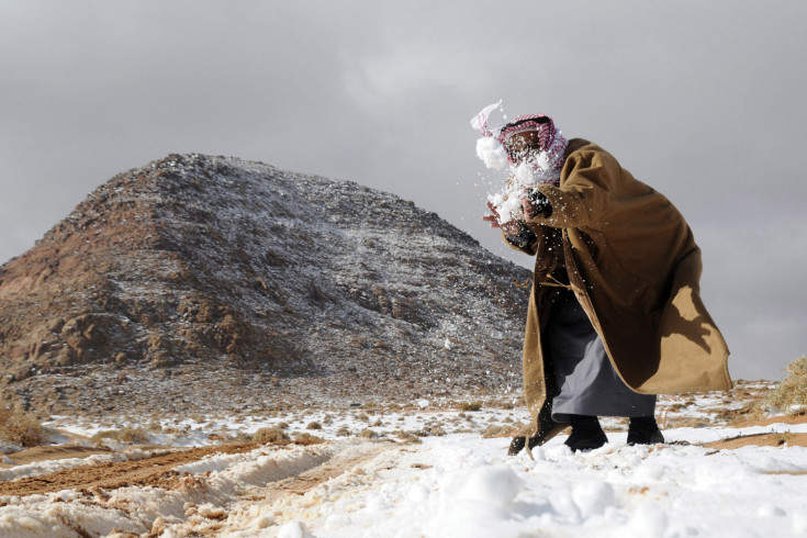 A man plays with snow after a snowstorm in the desert, near Tabuk
