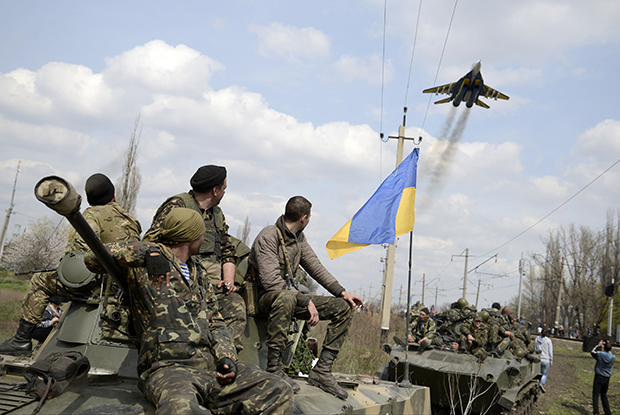 Ukrainian servicemen look at a Ukrainian military jet fly above them while they sit on top of armoured personnel carriers in Kramatorsk April 16, 2014. Ukrainian government forces and separatist pro-Russian militia staged rival shows of force in eastern Ukraine on Wednesday amid escalating rhetoric on the eve of crucial four-power talks in Geneva on the former Soviet country's future. REUTERS/Maks Levin (UKRAINE - Tags: MILITARY POLITICS CIVIL UNREST)