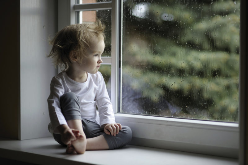 Adorable toddler girl looking at raindrops